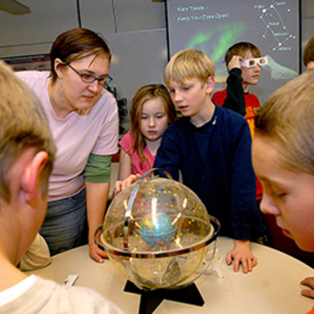 Kids looking at a clear globe at a science museum