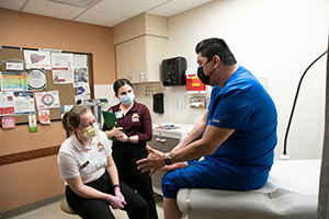 A patient during a physical therapy visit with providers in an exam room