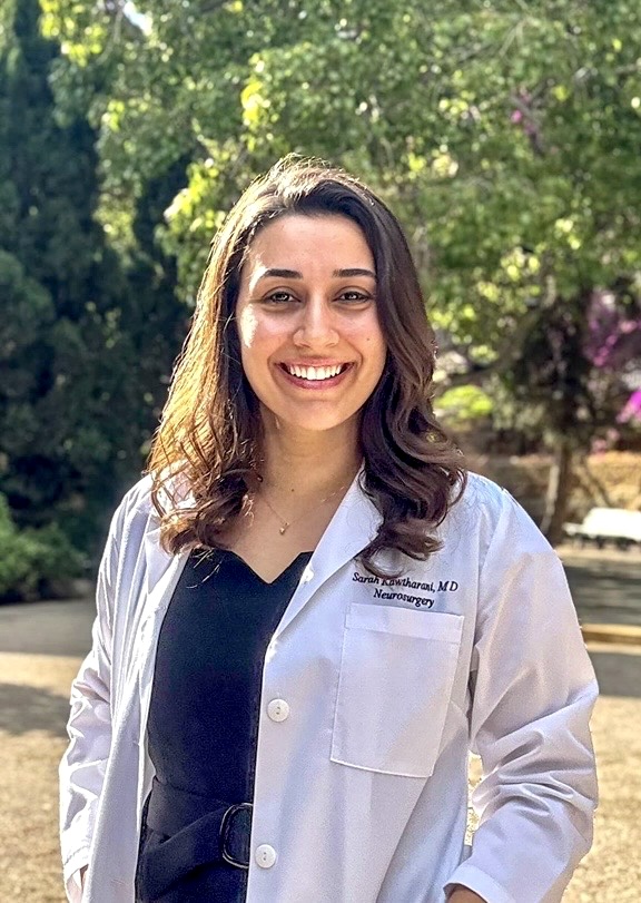 picture of a woman with curly hair smiling while wearing a lab coat