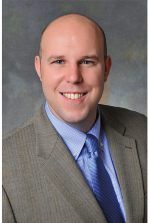 Dr. Steve Dunlop, a smiling bald white man in a grey suit