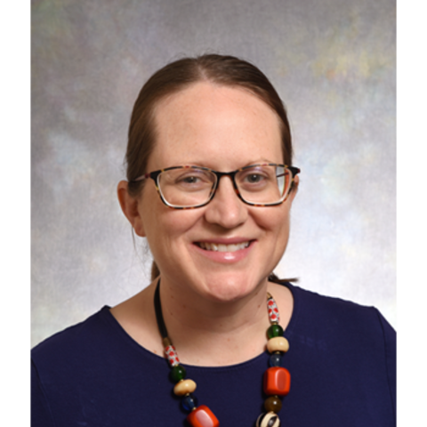 Dr. Megan Shaughnessy, a smiling white woman wearing glasses and a beaded necklace