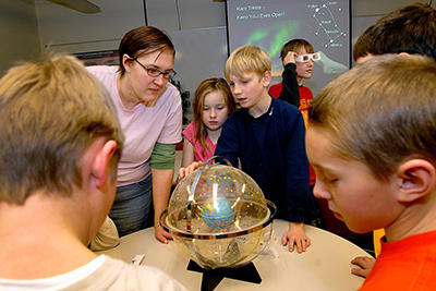 Kids looking at a clear globe at a science museum