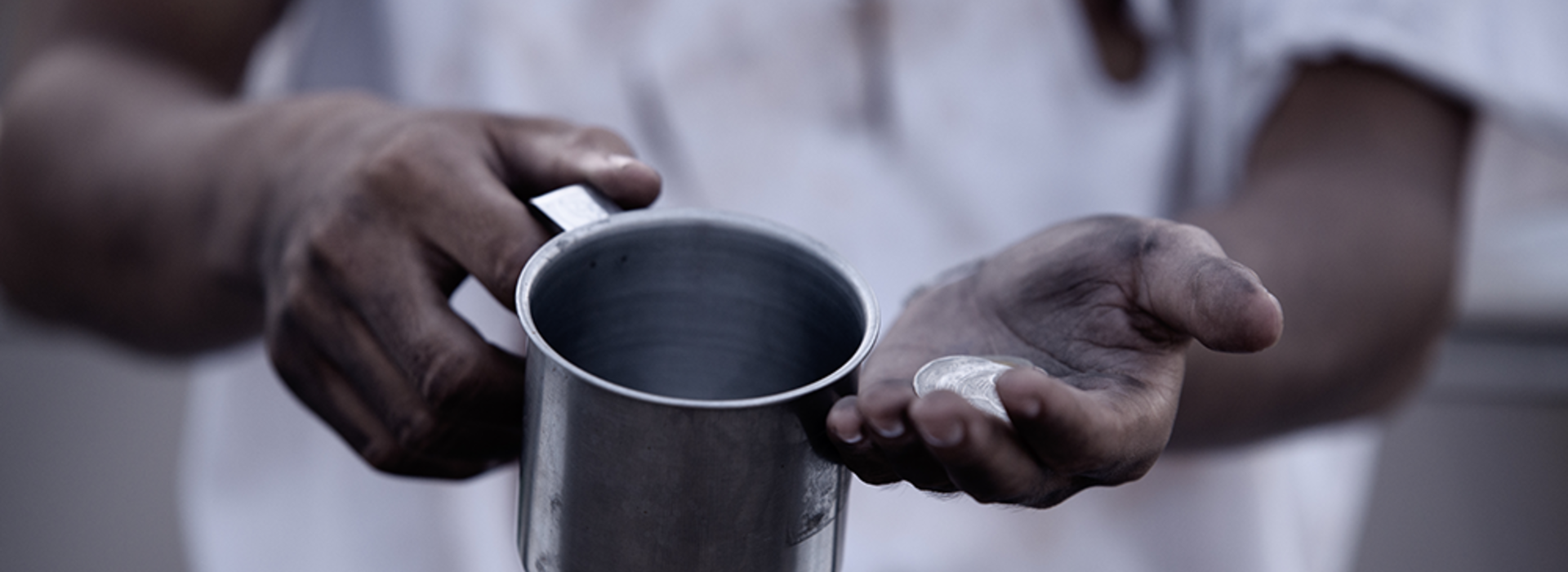 A Black man's hands holding a cup and coins.
