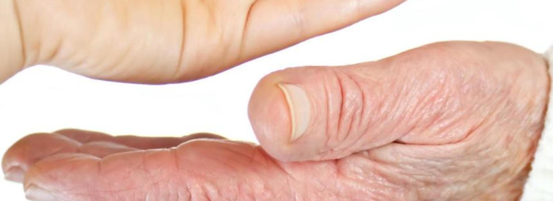 Hand dropping pills into an elderly person's hand
