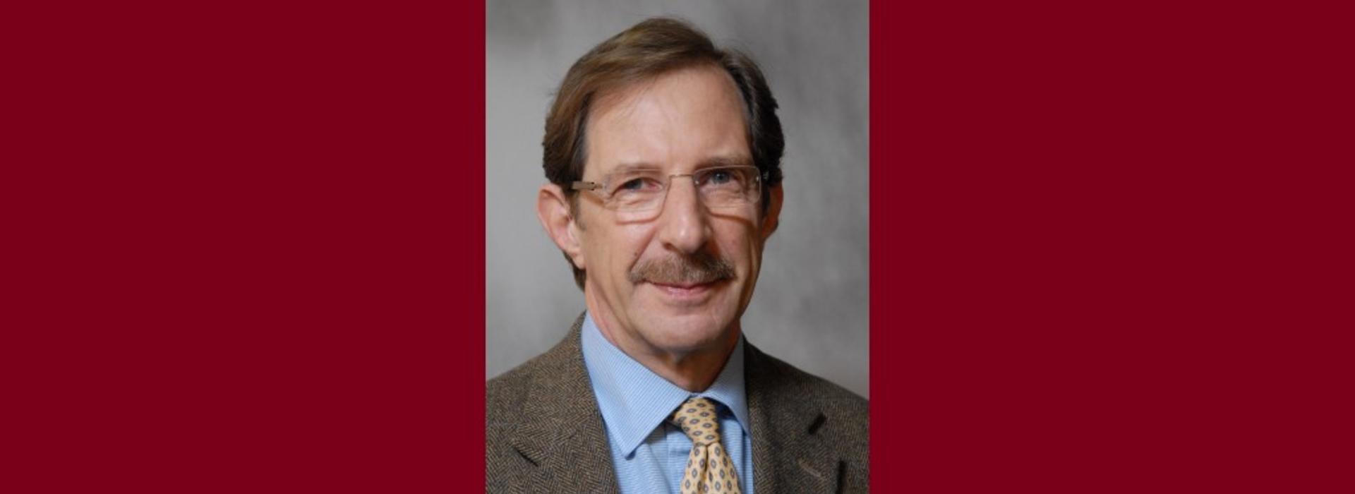 Headshot of Dr. Michael Mauer in front of a maroon background. 
