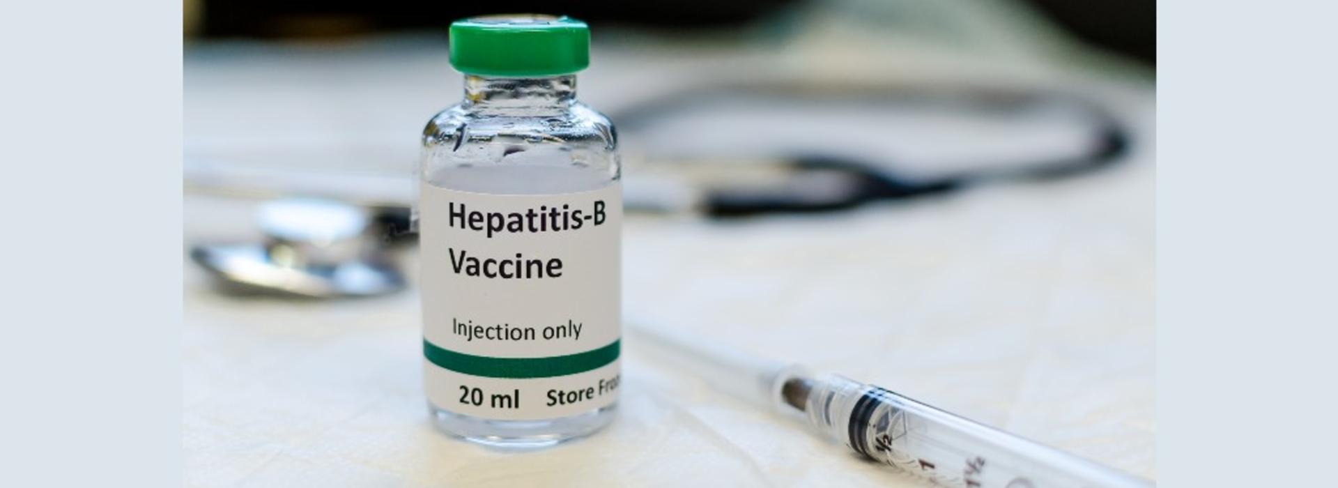hepatitis B vaccine vial with syringe and stethoscope in the background