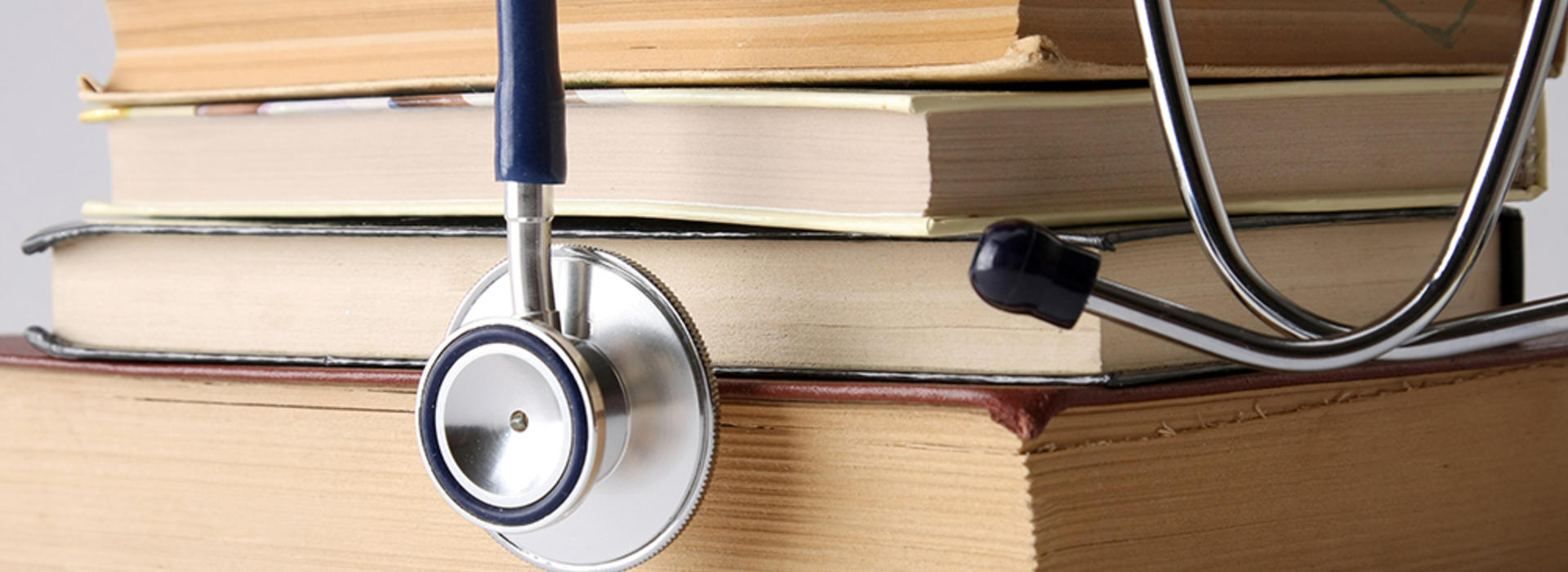 A stack of books with a stethoscope hanging over top of them.