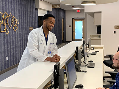 A doctor in a white coat talking to a front desk worker at Willmar rural family medicine residency