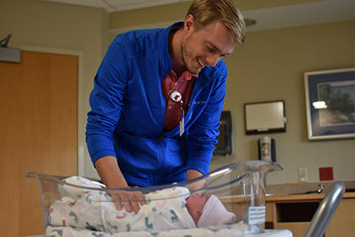 Dr. Nelson leaning over a newborn and smiling at Willmar rural family medicine residency
