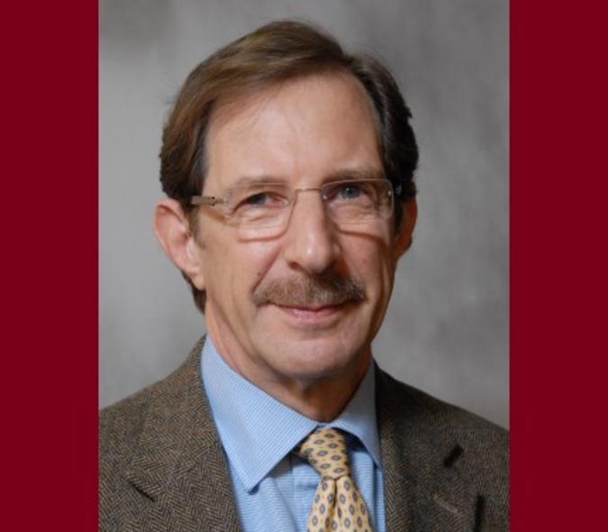 Headshot of Dr. Michael Mauer in front of a maroon background. 