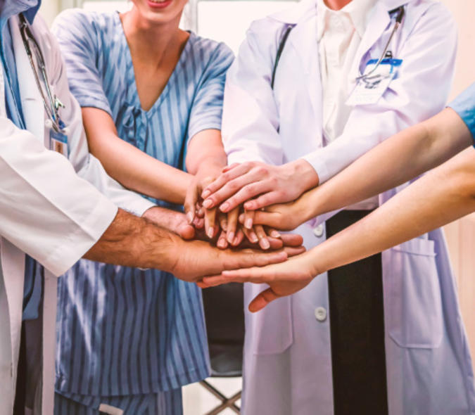 Medical providers putting their hands out together as a team