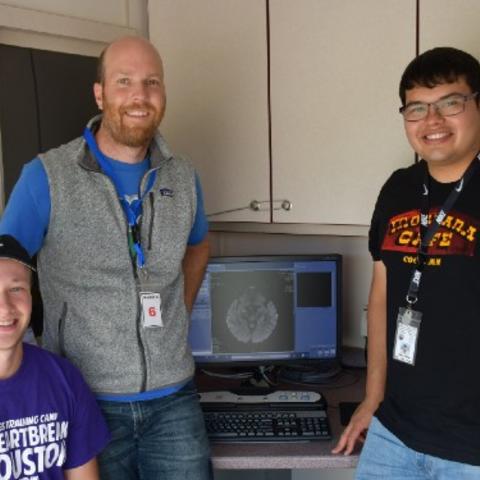 Research team poses next to brain scan on computer. 