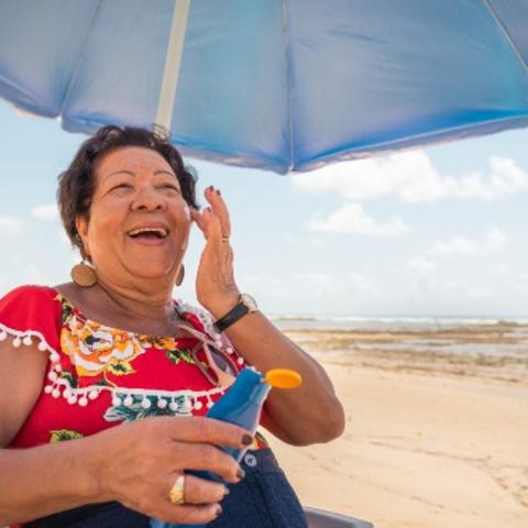 Senior woman using a suntan lotion on the beach