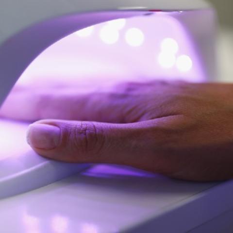 Hand underneath UV light dryer. 