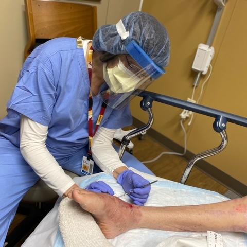 Sandra Rosenberg working on a patients wound