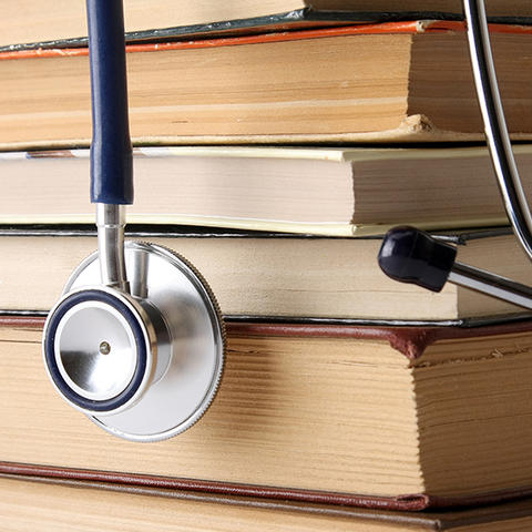 A stack of books with a stethoscope hanging over top of them.