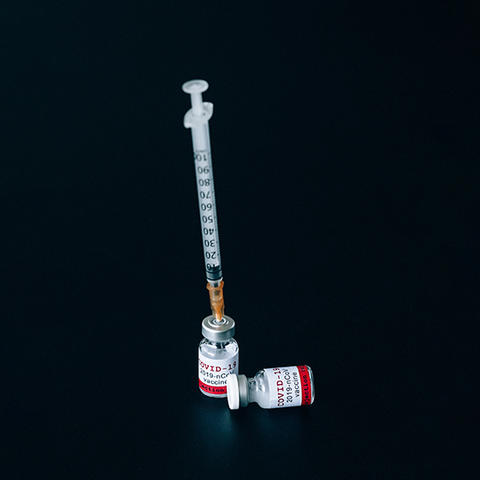 A syringe inside of a bottle labeled COVID-19 vaccine.