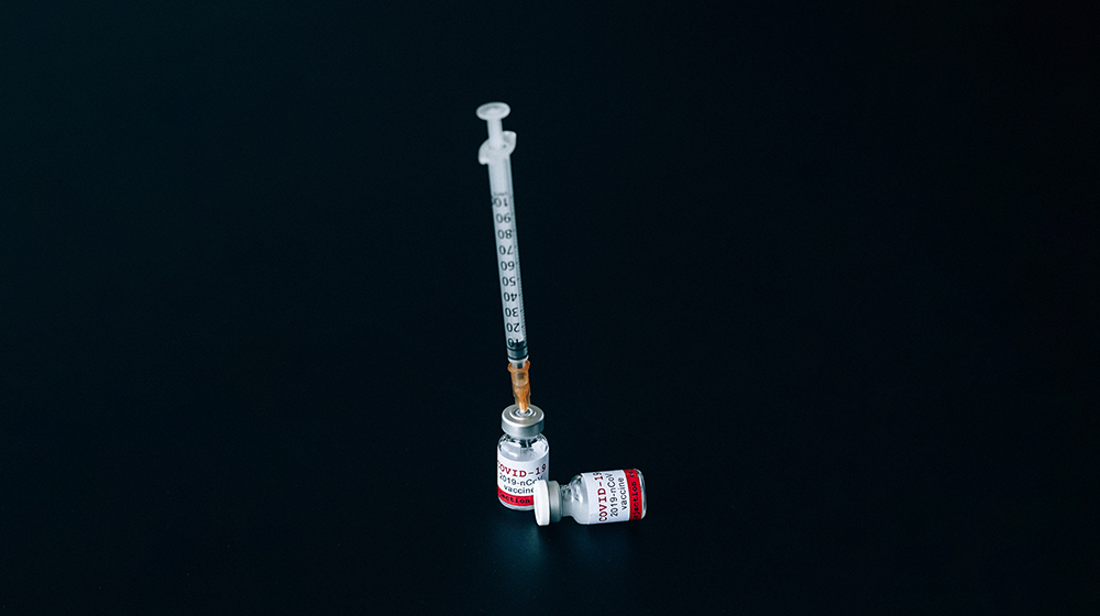 A syringe inside of a bottle labeled COVID-19 vaccine.