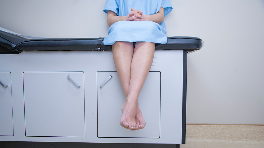 A woman sitting on a patient table.